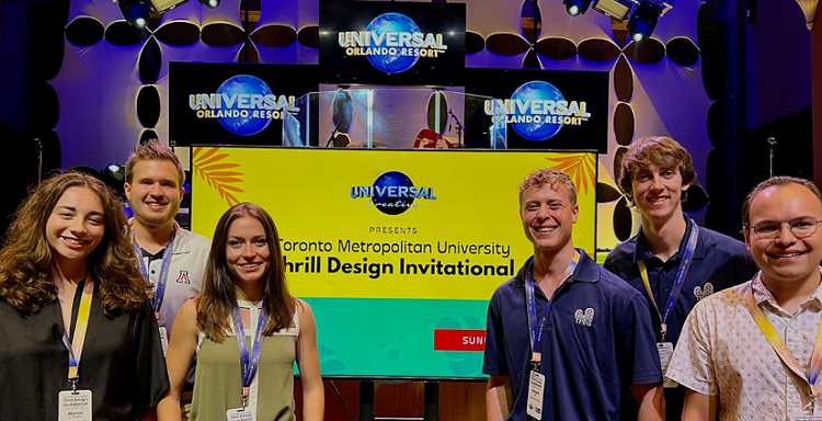 group of students, smiling in front of banner