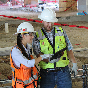 two people wearing safety helmets on a construction job site