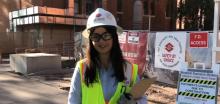 Andrea Flores in white Sundt hard hat and reflective vest, standing by UA Student Success District construction site