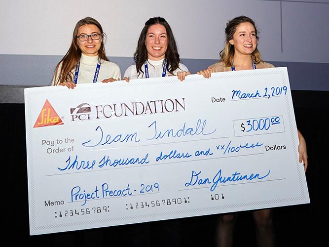 Three women holding a giant check for $3,000