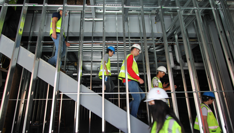 Civil engineers walking through the framework of a building wearing yellow construction vests