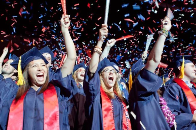 student in regalia, cheering