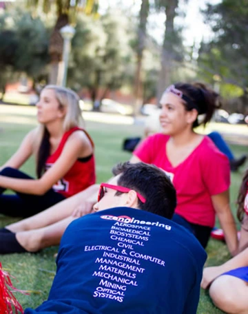 three students on lawn, one student wearing sunglasses