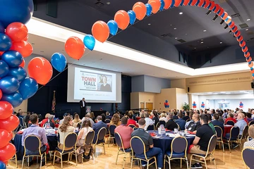 ballroom with people seated at tables and balloon canopy