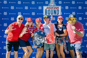 group of people holding U of A mascot and misc items